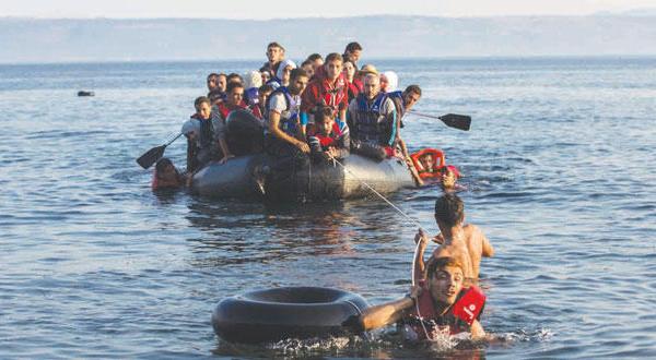دو پناهنده در حال کشیدن یک قایق حامل پناهندگان سوری و افغانی که از ترکیه به سواحل جزیره لیسبوس یونان رسیده اند – عکس از آسوشیتد پرس