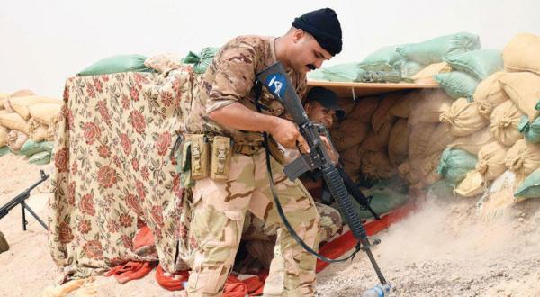یکی از نیروهای امنیتی عراقی در پشت سنگر خاکی در خط مقابل سازمان داعش در حومه شهر رمادی مرکز استان انبار در عراق – عکس از خبرگزاری فرانسه