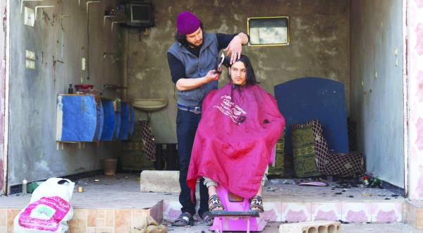 یک سوری در حال کوتاه کردن موهای خود در یک آرایشگاه آسیب دیده در شهر غربی الغاریه در استان درعا که تحت کنترل مخالفان است – عکس از رویترز